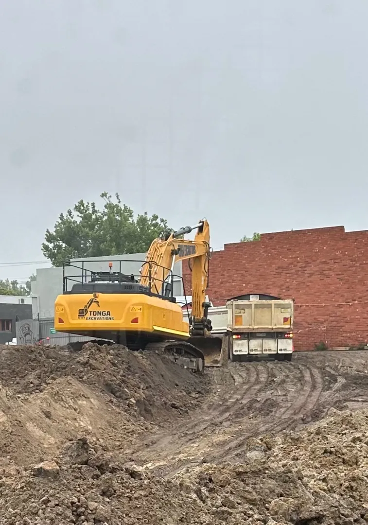 Excavator loading dirt into dump truck at construction site.